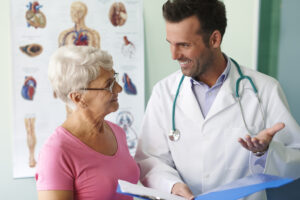 Idosa passando por consulta com um jovem médico, que sorri com boas notícias.