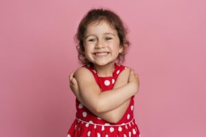 menina sorridente com um vestido vermelho, fazendo referência a um plano de saúde para crianças.